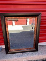 Full view of the wooden framed mirror with beveled glass showing the two-tone wooden frame and reflection.