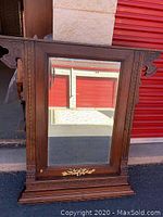 Full view of antique wooden carved mirror showing detailed woodwork and reflection
