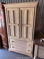 Front view of distressed white wooden hutch with two paneled cabinet doors and a lower drawer, knobs intact.