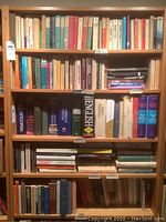 Front view of the bookcase fully loaded with books, showing condition and shelf structure