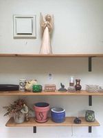 Shelf with assorted decorative items including tall angel figurine, various small vases, plant pots, and floral arrangement