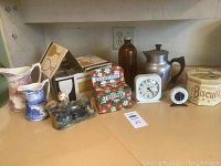 Vintage kitchen items including pitchers, recipe boxes, clocks, and other kitchenware arranged on a counter.