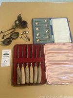 Wide view of all items: spoon sets, knife set, condiment containers, strainers and small spoons