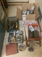 Full lot overview showing boxes, license plates, clamps, keys and other tools on the floor.