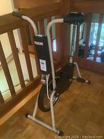 Photo showing entire CCM vintage exercise bike, black and white steel frame, rubber grips on handlebars, padded seat.