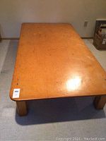 Front view of wooden bed platform showing rectangular top with rounded edges and four legs.