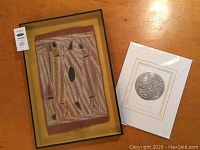 Both framed artworks side by side on wood surface