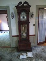 Full front view of tall-case clock showing wooden case and base