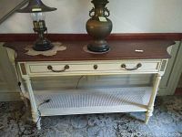Full front view of vintage painted wood console table with finished wood top, rattan shelf, and one drawer.