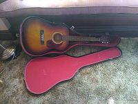 Full view of Harmony acoustic guitar with case on carpeted floor