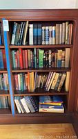 Full shelf view of vintage hardcover books on wooden shelving unit