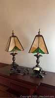Pair of 18-inch table lamps on wood surface with stained glass shades and ornate metal bases