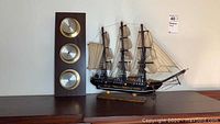Barometer mounted next to model ship showing overall size and condition