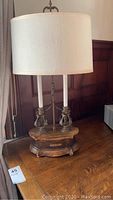 Full view of the Frederick Cooper 29 inch table lamp showing the two candle style bulbs and the fabric shade on a wooden surface