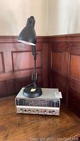 Front view of black metal desk lamp standing on Band Spread radio S-120 with control panel.