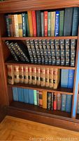 Bookshelf showing sorted vintage encyclopedia sets (Encyclopedia Britannica, Encyclopedia Americana) and legal books with worn bindings.