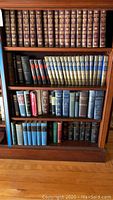 Bookshelf with multiple rows of vintage hardcover books, including Encyclopaedia Americana and other reference volumes, some with visible wear.