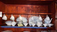 Full view of the Royal Bayreuth china tea set and serving pieces displayed on shelf.