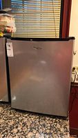 Front view of silver and black Whirlpool mini fridge with logo on door.