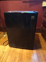 Front view of the black Kenmore mini fridge closed, showing the exterior and logo.