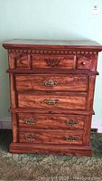 Front view of wooden dresser with 5 drawers, showing decorative detailing and condition