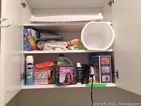 Image showing open cabinet with assorted cleaning supplies, hand towels, hair curlers, and Conair hair straightener