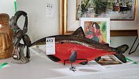 Fish-shaped decorative plate painted red with silver and black, size tag attached showing dimensions 23x8 inches.