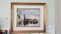 Framed oil painting showing harbor buildings, boats, and a cloudy sky with visible signature 'Collin'.