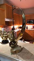 Side view of metal sailboat sculpture with curved sail on resin base
