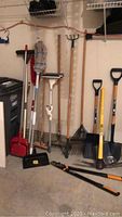 Photo showing all garden and cleaning tools including rakes, shovels, pick, hedge clippers, mops, broom, and scrub brush