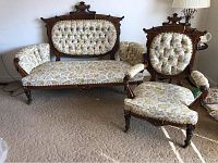 Two-piece Victorian Eastlake settee and chair set with floral upholstery and carved wooden frames.