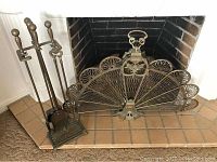 Full view of brass fireplace screen and matching tool set arranged in front of fireplace.