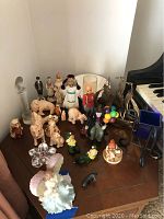 Wide view showing the lot of various collectible figurines including ceramic elves, Sitka clay animals, Hummel, and Royal Doulton figurines arranged on a wooden surface next to a piano keyboard.
