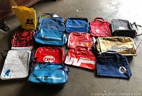 Photo showing the majority of the vintage airline and travel bags laid on floor, various colors and logos visible