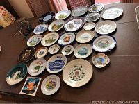 Overview of various porcelain and ceramic collectors plates displayed on table, showing different sizes and designs