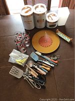 Full lot including canisters, glassware, tray, spice rack, and cooking utensils arranged on table.