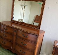 Full view of dresser with attached mirror showing curved fronts and wood grain finish.