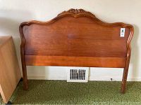 Full width view of the cherry wood headboard showing the curved top with embellished carvings.