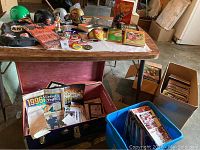 Wide view of table with helmets, scarves, buttons, figurines, and boxes of vintage sports magazines and programs.