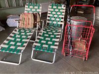 Two folding chaise lounge chairs and other related items grouped together in a garage or storage area.