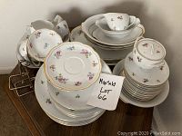 Full view of the china set arranged to show cups, saucers, plates, bowls, and serving pieces with floral patterns and gold trim.