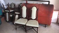 Set of four upholstered wooden dining chairs with cream patterned upholstery and stained wooden frames, some surface wear and stains visible.