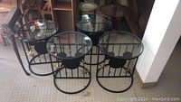 Four round side tables with black metal frames featuring Mickey Mouse ear silhouettes and glass tops.