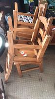 Four wooden dining chairs stacked upside down showing wear and construction details.