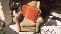 Wing back chair front view showing overall condition with two orange pillows on seat.