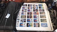Seven large uncut sheets showing grids of baseball cards and stadium photos, mostly featuring players from the New York Yankees, placed on black fabric with visible wear on some edges.