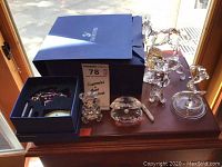 Eight figurines arranged on wooden surface with blue Swarovski box behind