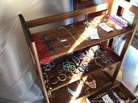 3 tier wood shelving unit with visible wood grain, dark brown color, shown empty or with jewelry not included in sale.