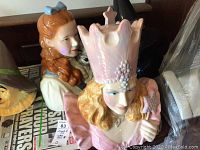 Front and side views of Glinda and Dorothy cookie jars with Wicked Witch and Tin Man partially visible in background.