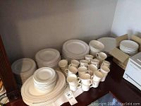 Wide view of the dishware set showing plates, bowls, cups and saucers arranged on a table.